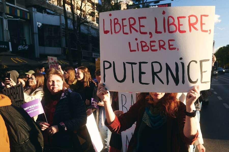 Participante la un protest, cu pancarta «Libere, libere, libere, puternice»