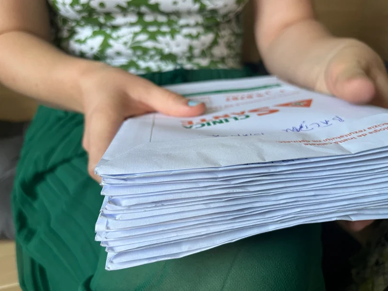 O femeie ține în mâini plicuri cu documente medicale