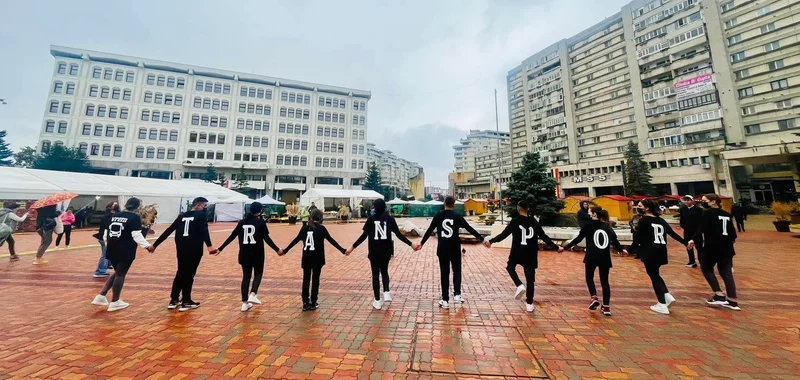 Tineri la un flashmob în spațiul public, purtând literele cuvântului transport