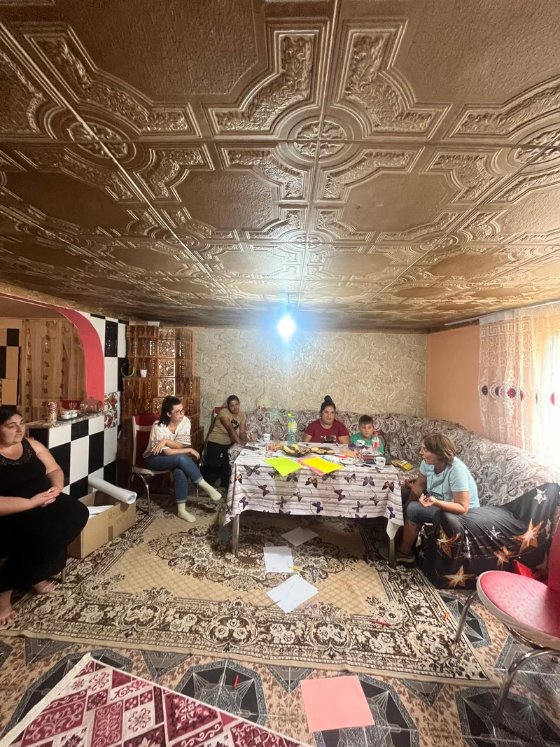 Participante la o întâlnire comunitară în Hârtiești, așezate în jurul unei mese